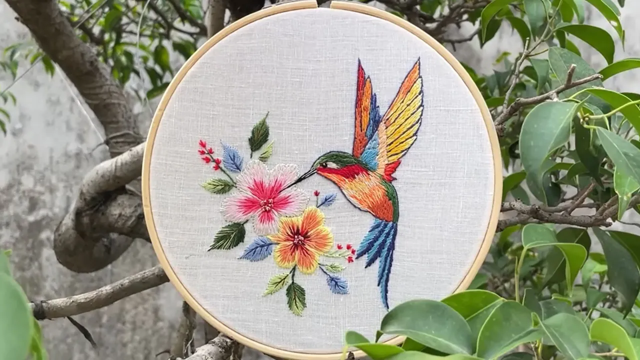 Detailed hand-embroidered bird and flowers showing colour blending and stitch direction