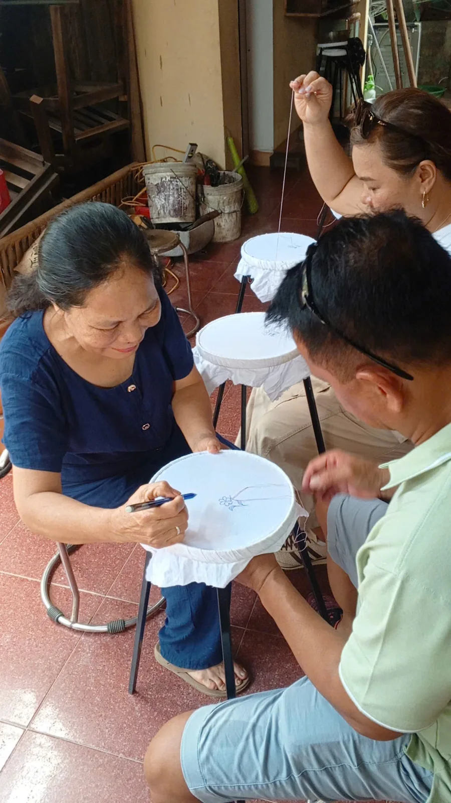 Dinh Thi Nguyen demonstrating hand embroidery technique to a visitor in Tam Coc