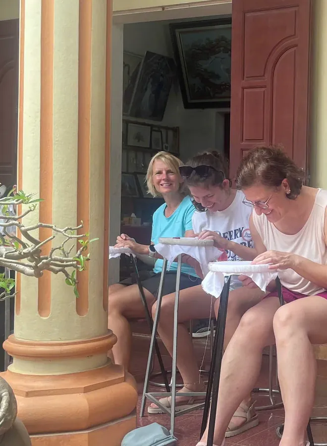 Guests concentrating on traditional hand embroidery at a workshop in Tam Coc
