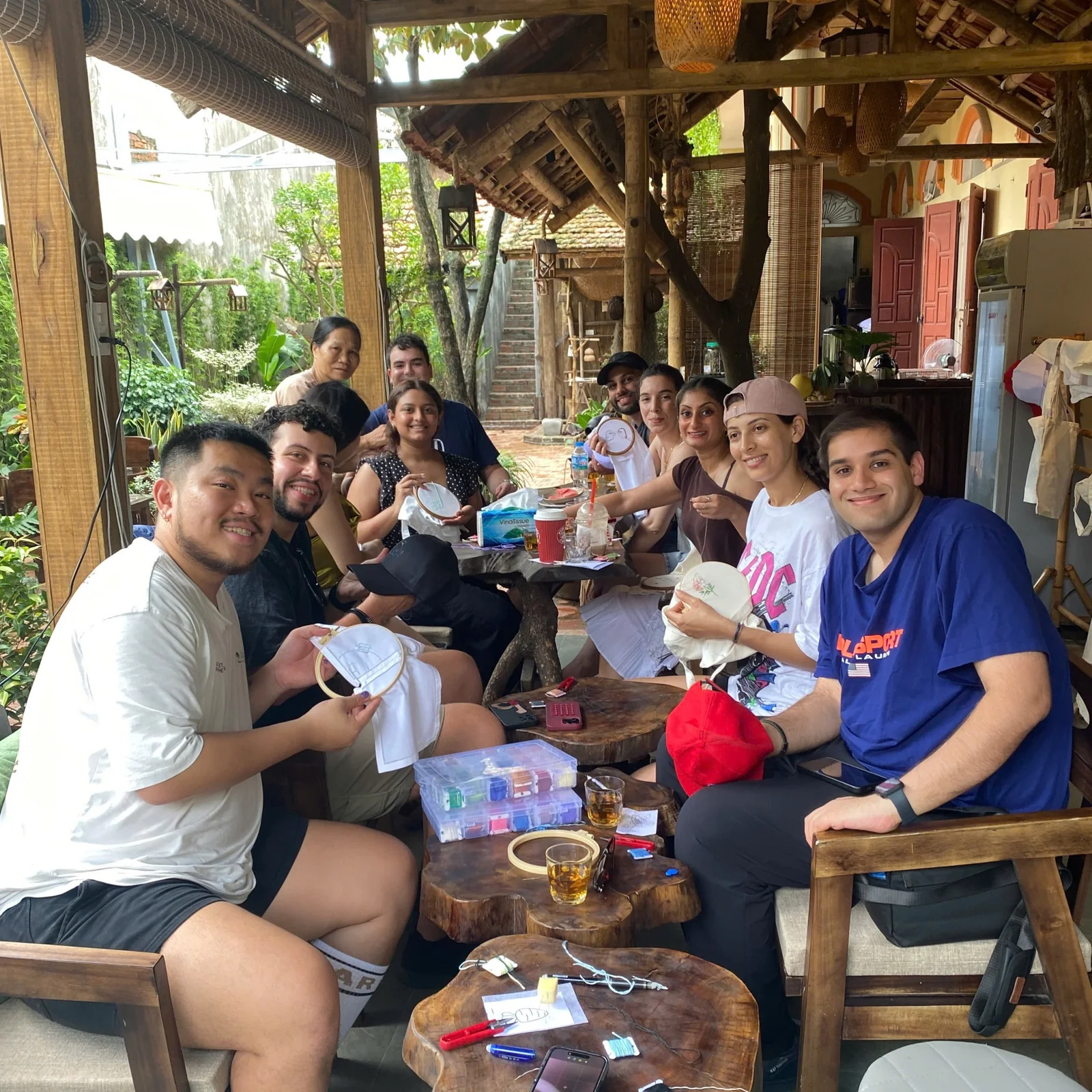Travelers holding handmade embroidery pieces during a family workshop in Tam Coc
